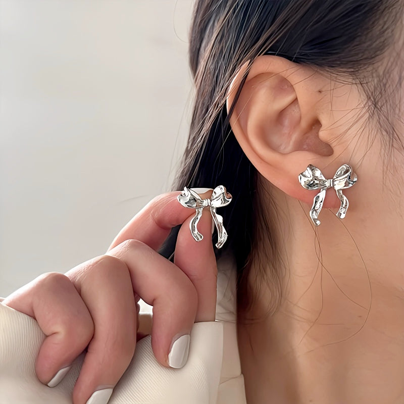 Imagine a delightful pair of earrings that exude charm and elegance. These drop earrings are designed in the shape of a sweet bow knot, giving them a playful yet sophisticated appearance. The earrings are lightweight and hang gracefully, swaying gently as you move.