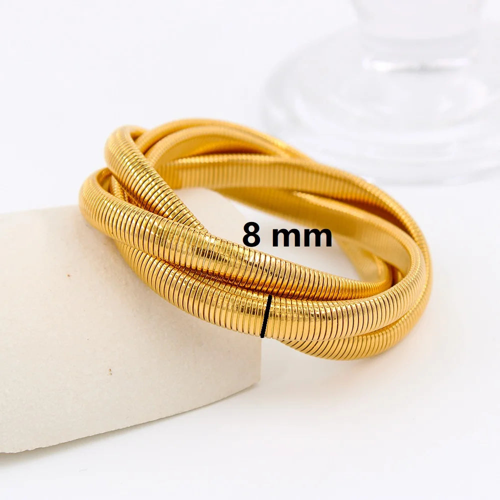 The image depicts a stylish bracelet with a ribbed design in a shiny rose gold color, suggesting it is made of 18k gold plated titanium. The bracelet features a twisted, interwoven appearance, giving it a unique and fashionable look. It appears to be a single, continuous band without clasps, showcasing its design.