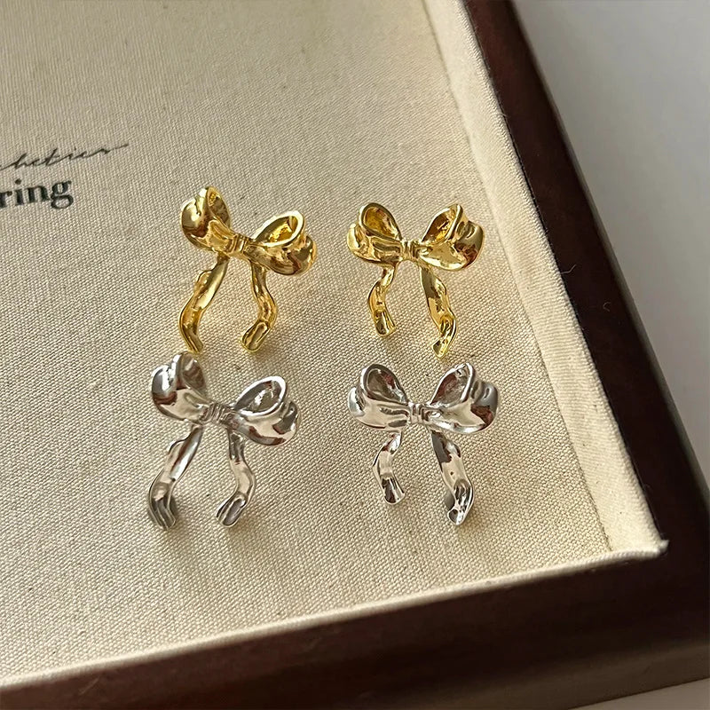 Imagine a delightful pair of earrings that exude charm and elegance. These drop earrings are designed in the shape of a sweet bow knot, giving them a playful yet sophisticated appearance. The earrings are lightweight and hang gracefully, swaying gently as you move.