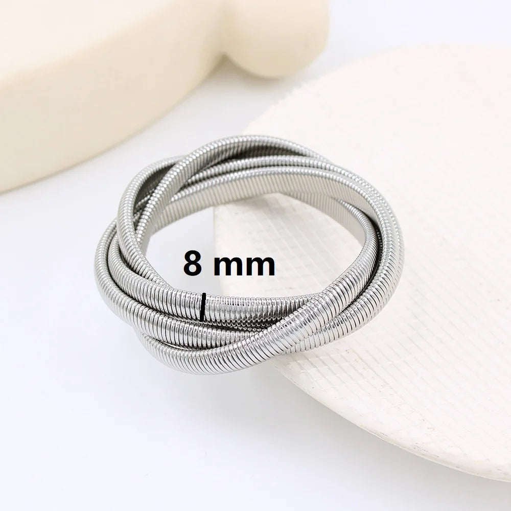 The image depicts a stylish bracelet with a ribbed design in a shiny rose gold color, suggesting it is made of 18k gold plated titanium. The bracelet features a twisted, interwoven appearance, giving it a unique and fashionable look. It appears to be a single, continuous band without clasps, showcasing its design.
