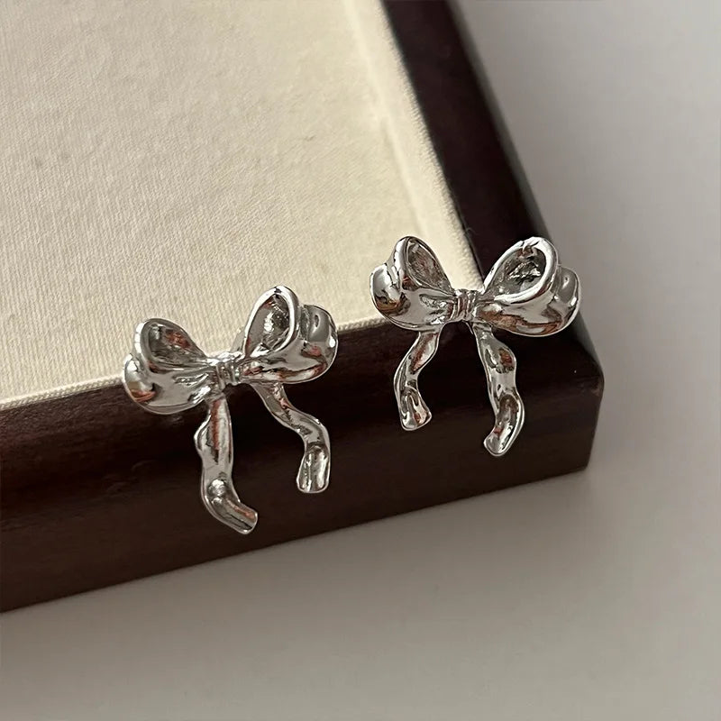 Imagine a delightful pair of earrings that exude charm and elegance. These drop earrings are designed in the shape of a sweet bow knot, giving them a playful yet sophisticated appearance. The earrings are lightweight and hang gracefully, swaying gently as you move.